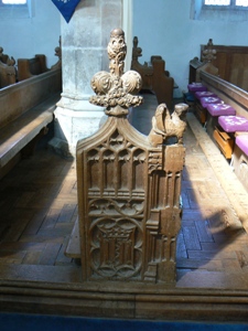 Carved bench end with figure on arm rest