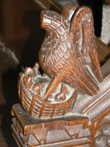 Carving of pelican with young on the arm rest