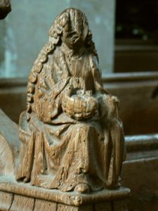 Arm rest carving of St. Dorothy with basket of flowers or fruit